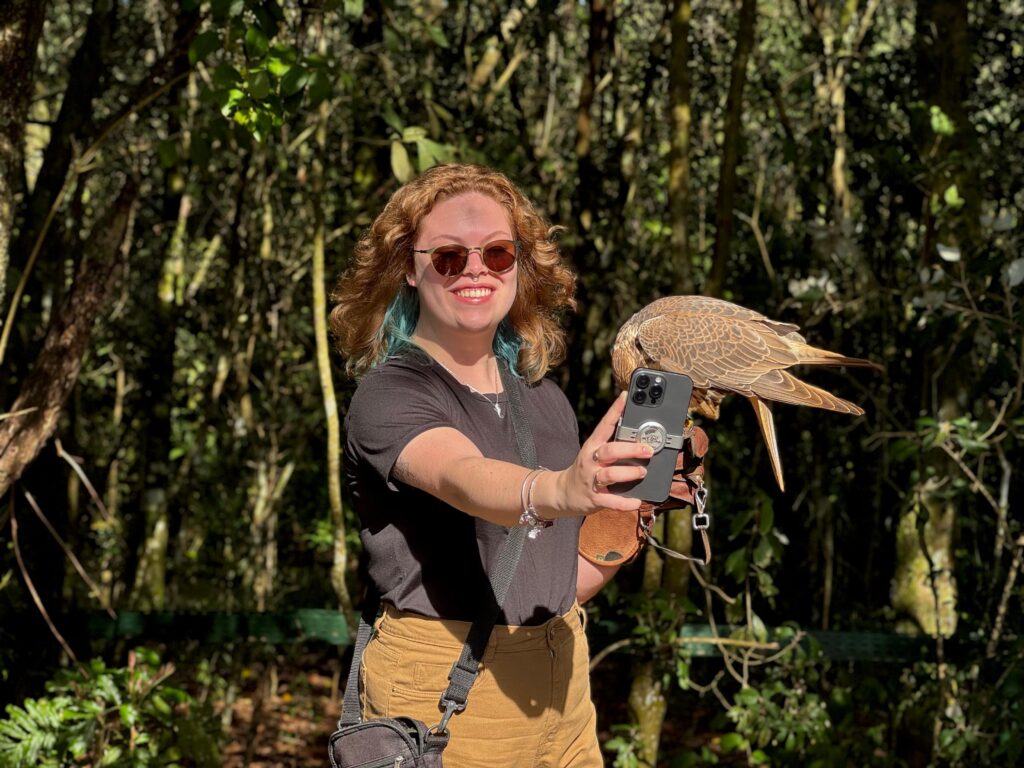 Mulher tirando selfie segurando uma ave com luvas de falcoeiro